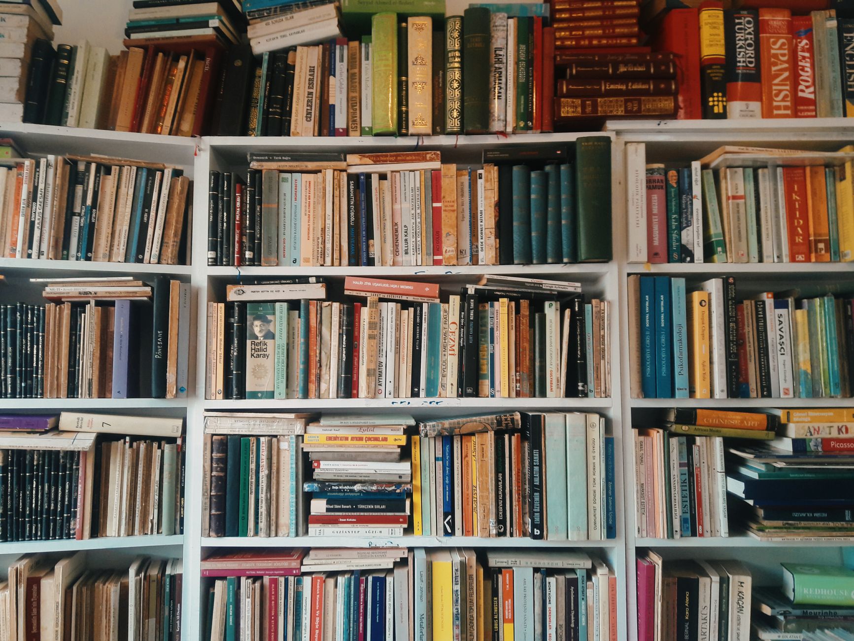 A cozy living room corner with books stacked in a decorative tower and stored in wicker baskets.