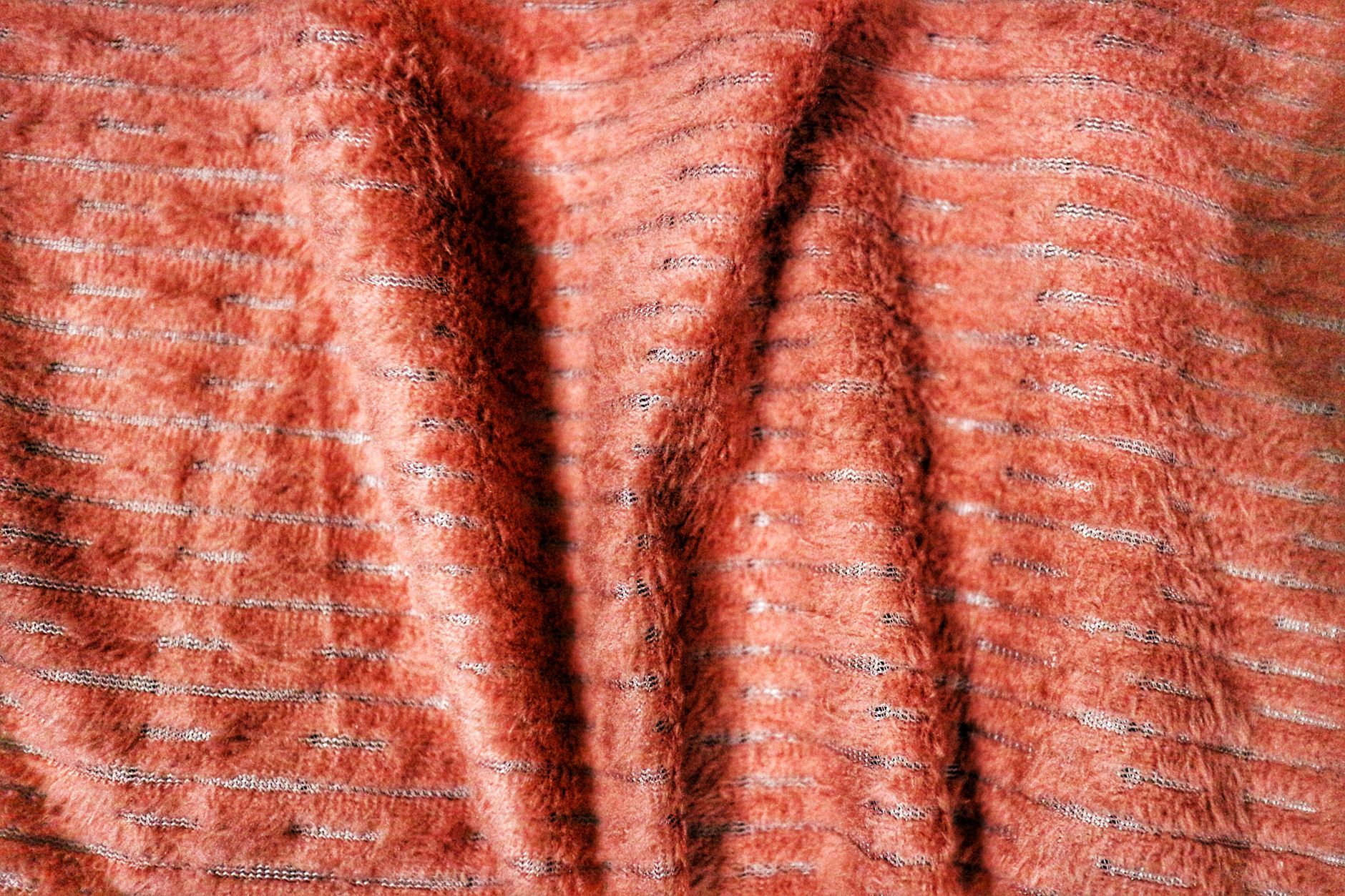Close-up of warm orange fabric with textured stripes, ideal for pattern backgrounds.