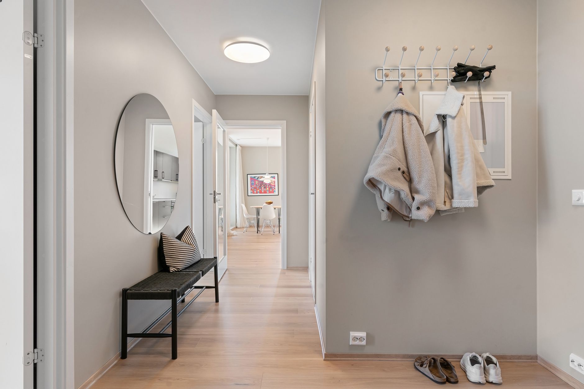 A welcoming and organized entryway with a wooden bench, hooks for coats, and a shoe rack