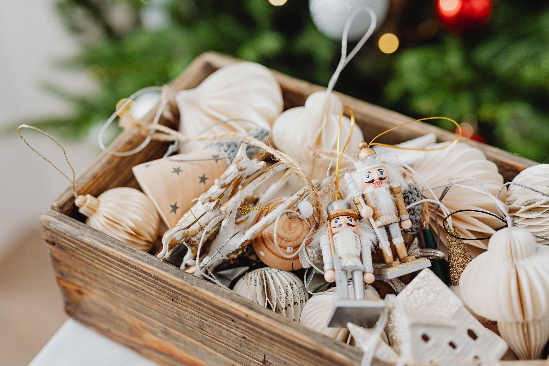A wooden box filled with elegant Christmas ornaments and nutcracker figures.