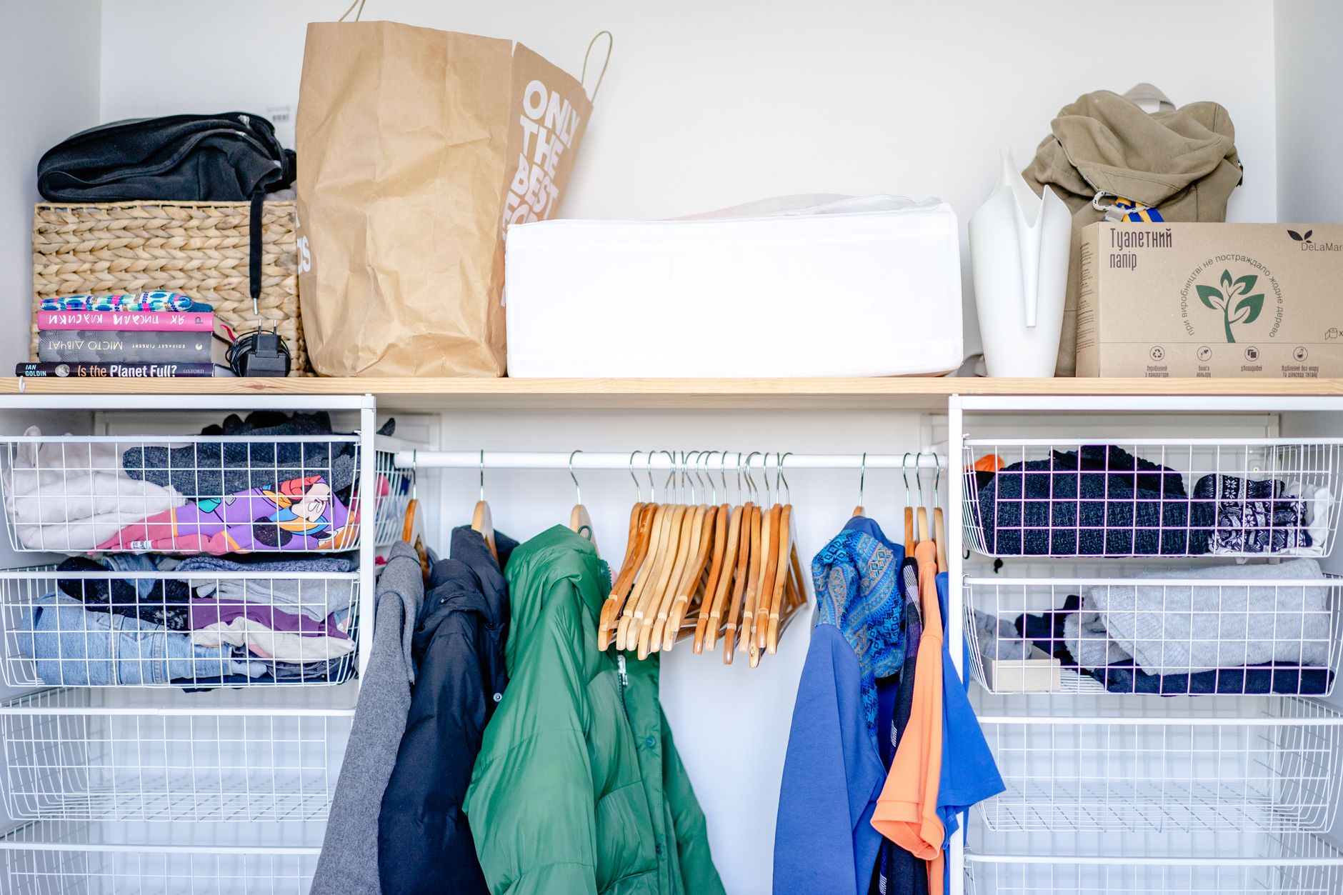 A neatly organized closet with clothes folded using the KonMari method and items arranged by color and category.
