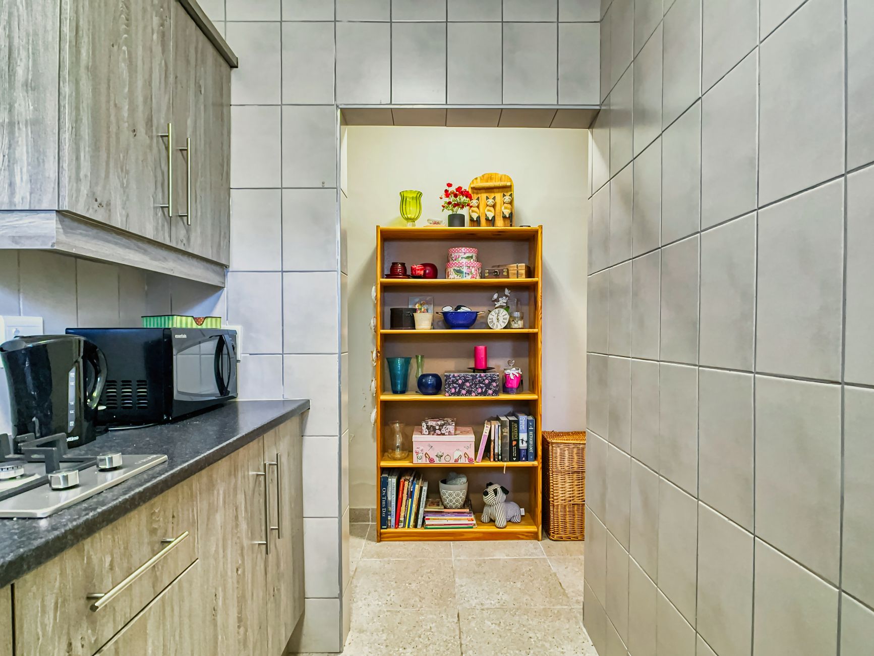 A living room with open shelving displaying books, plants, and decor items.