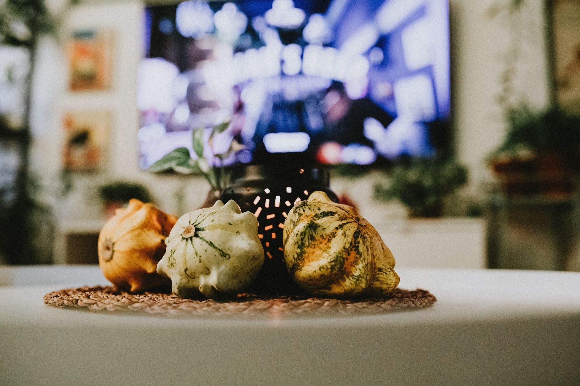 A cozy living room with fall-themed decorations, including pumpkins, warm blankets, and candles