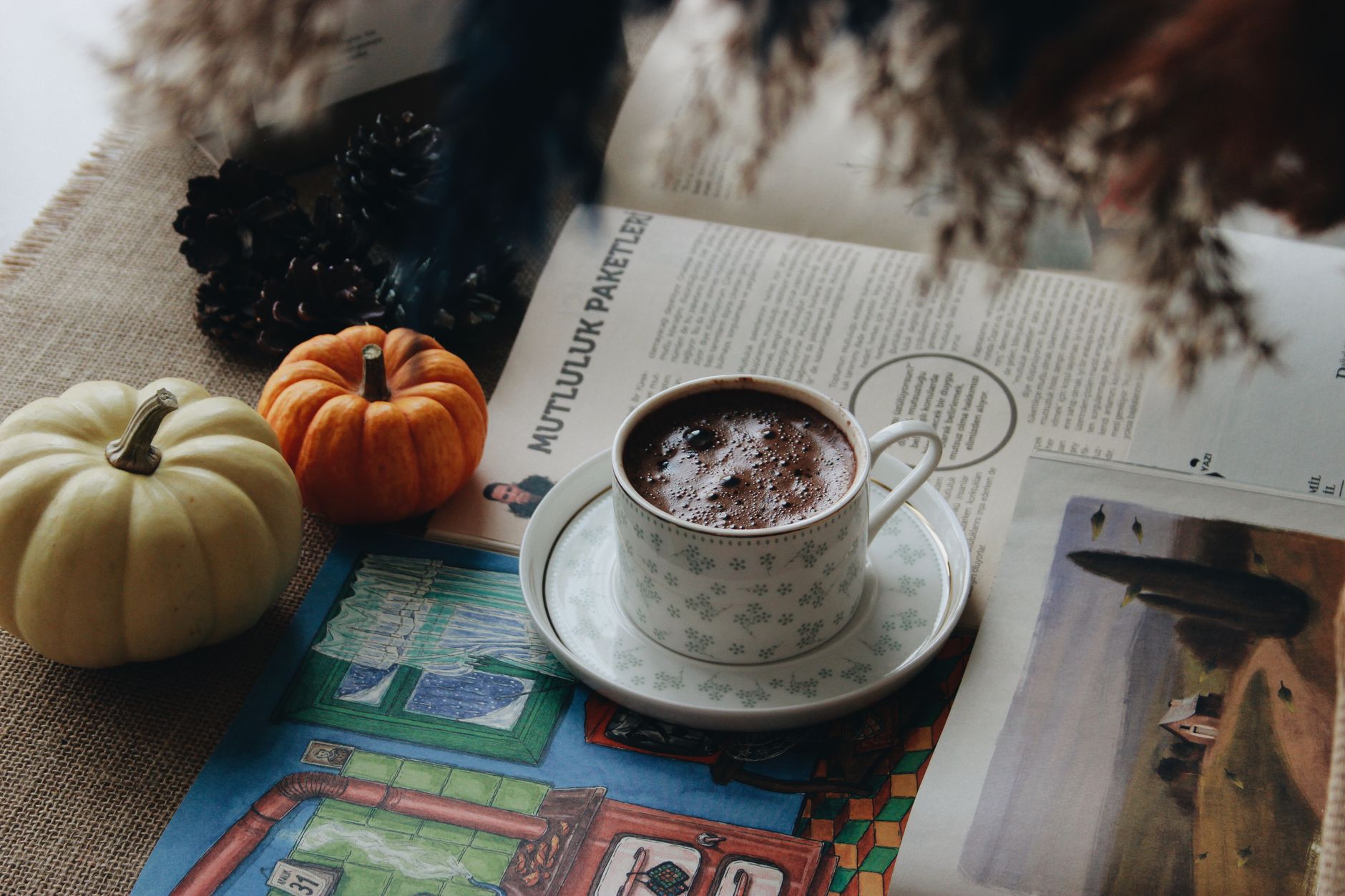 Cozy autumn scene with hot chocolate, pumpkins, and a magazine creating a warm atmosphere.